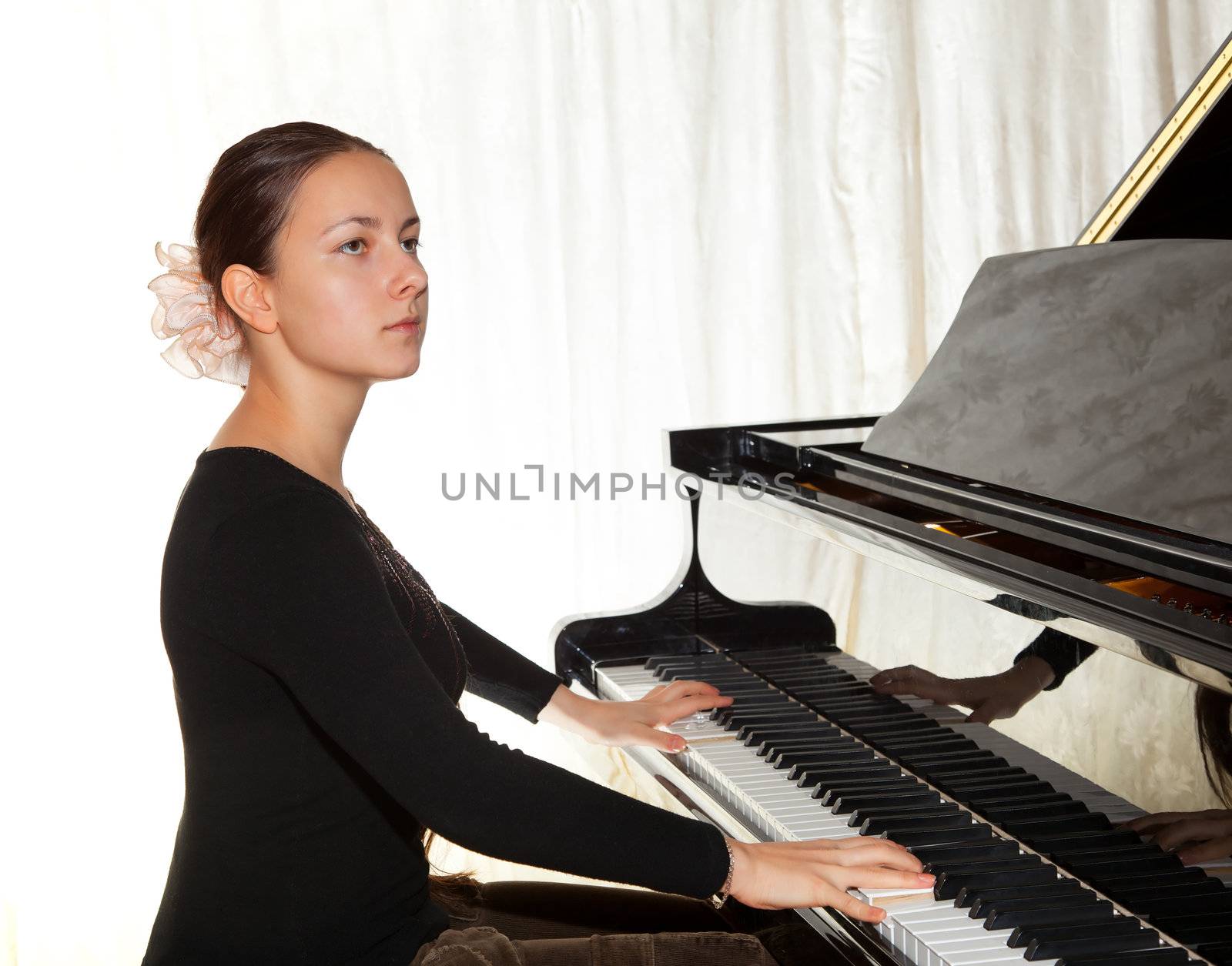 Young beautiful girl playing the piano with a raised lid