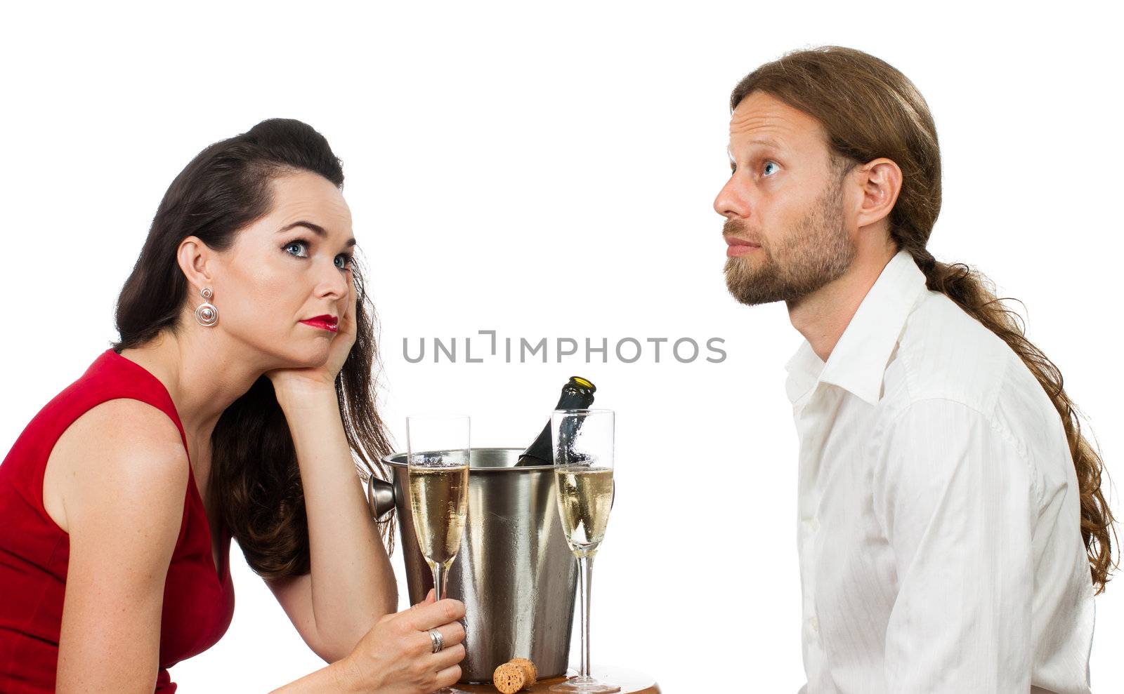 A bored couple out on a Champagne date avoiding eye contact. Isolated on white.