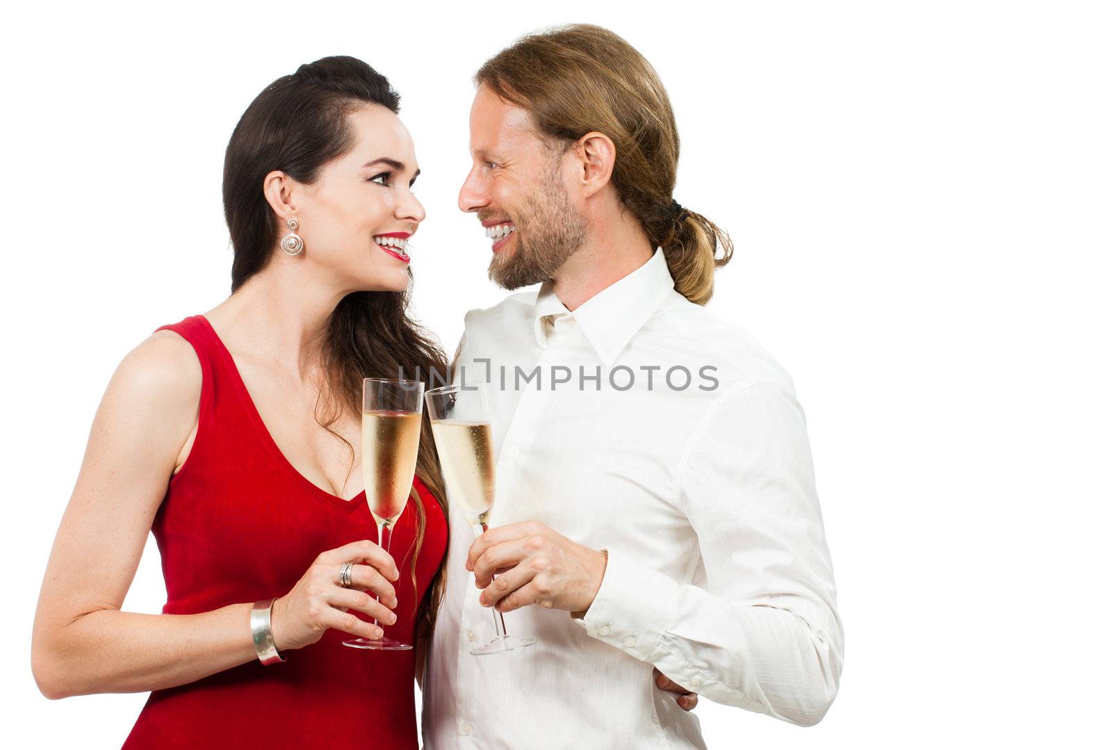 A happy couple in love looking at eachother while doing cheers with Champagne. Isolated on white.