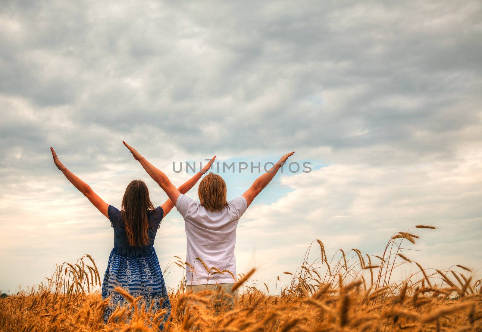 Couple staying with raised hands at a wheat field by AndreyKr