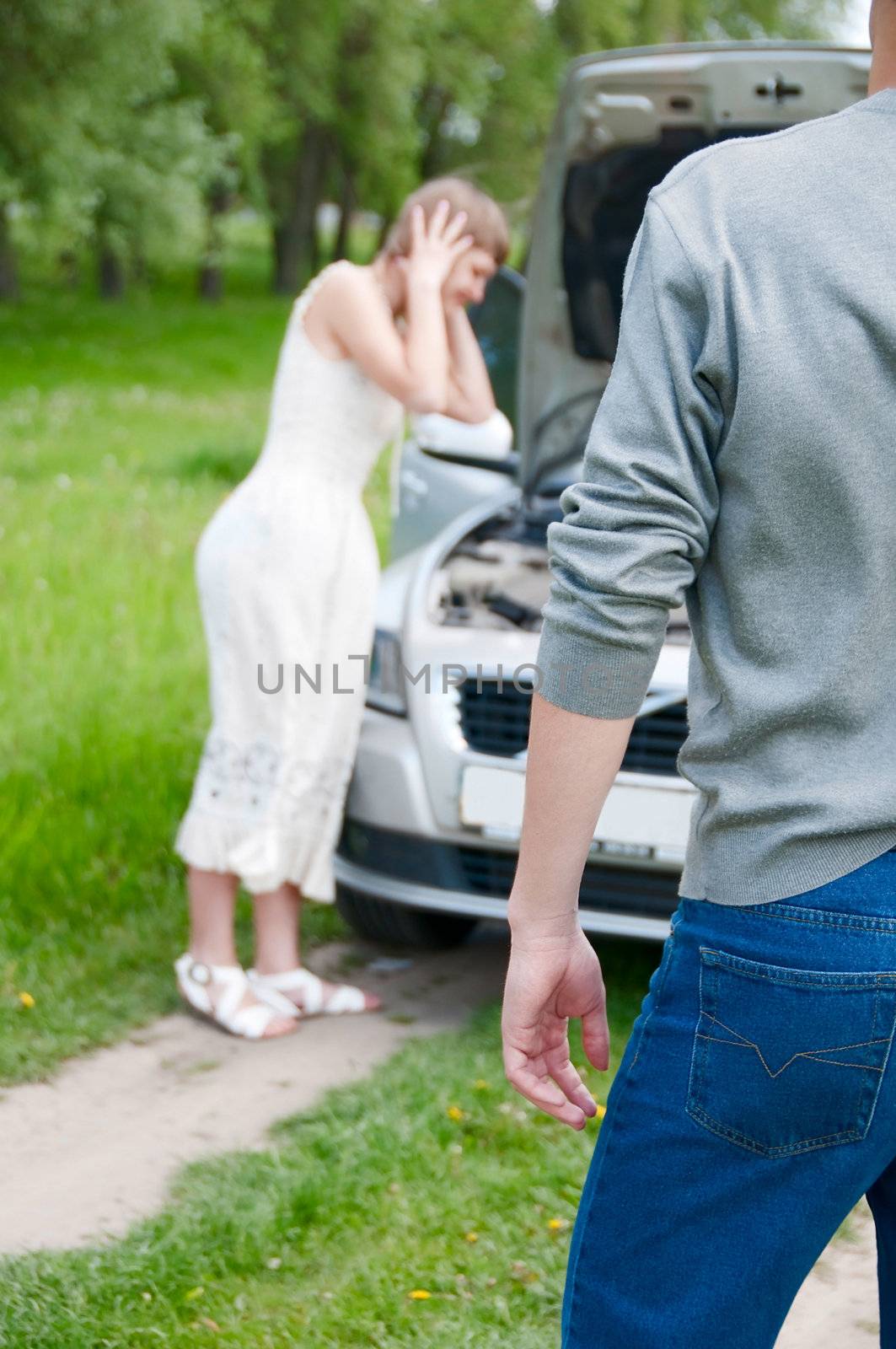 Male back with worried young woman near her broken car