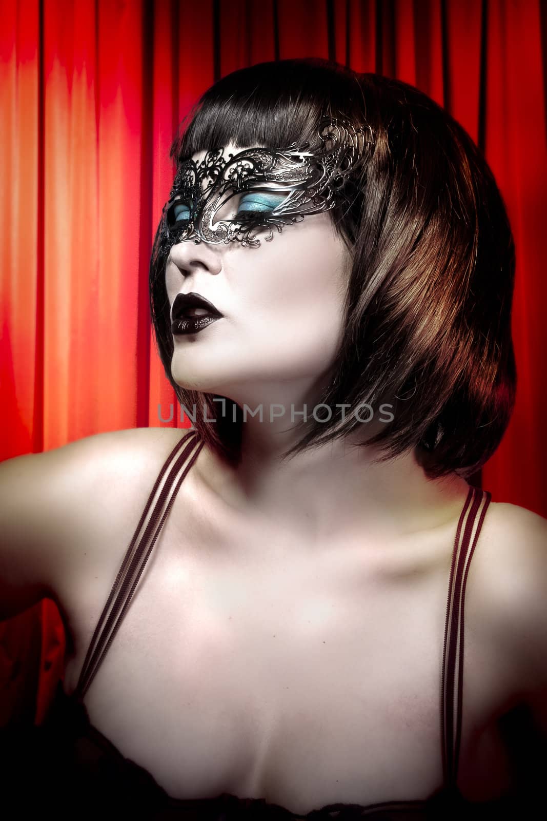 Young actress with venetian mask over cabaret background