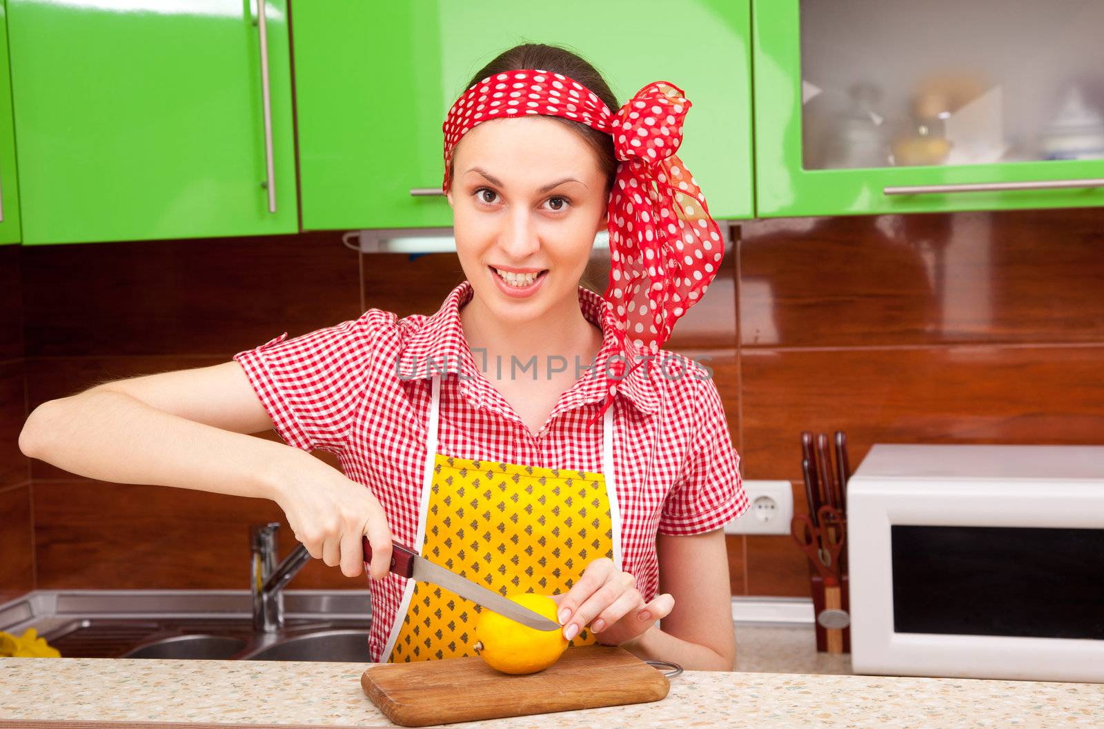 Woman in the kitchen is cutting a fresh lemon