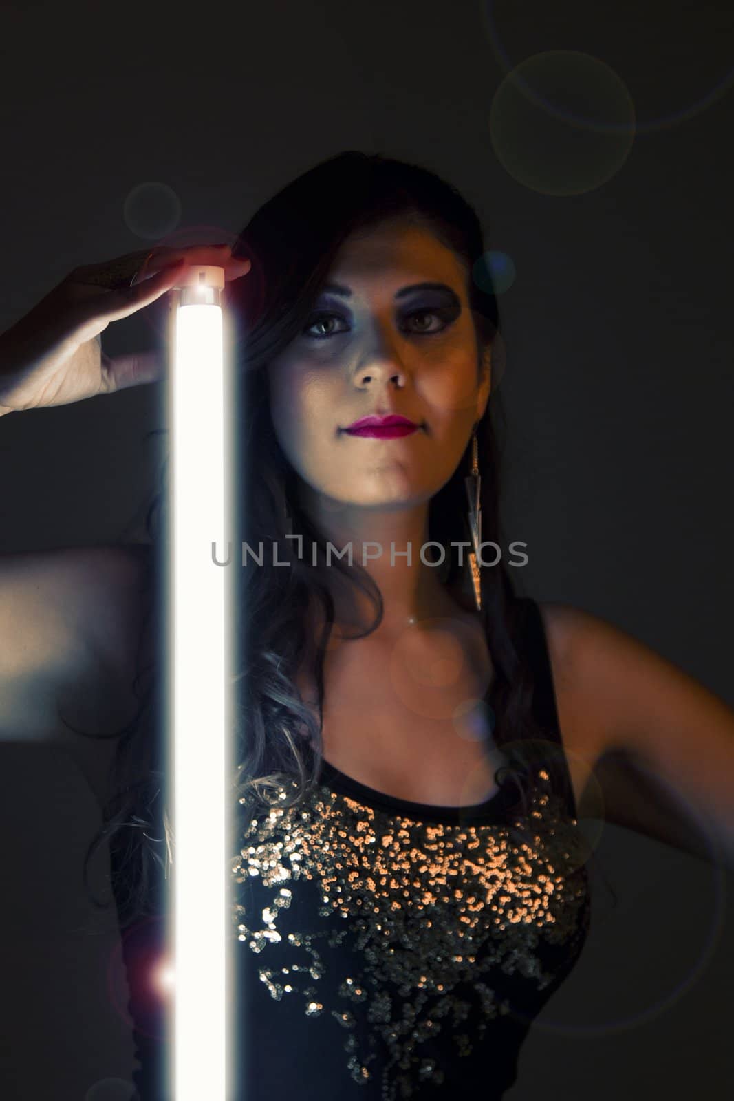 View of a beautiful girl in dark leather clothes holding a light tube.