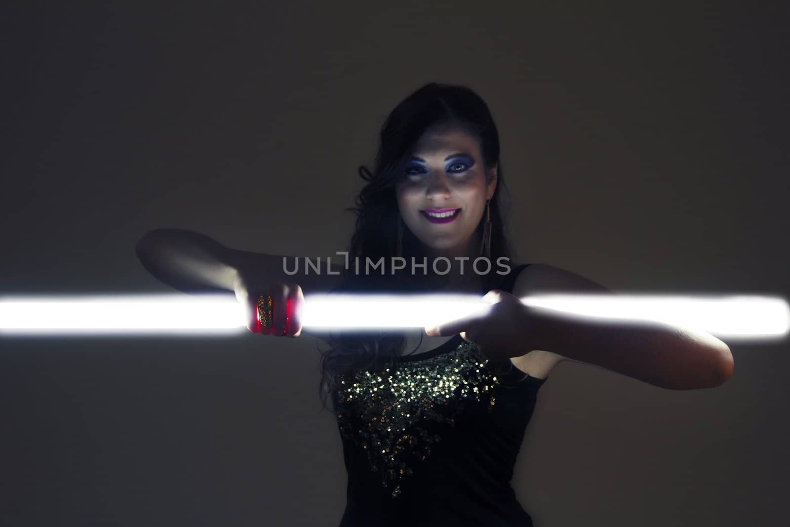 View of a beautiful girl in dark leather clothes holding a light tube.