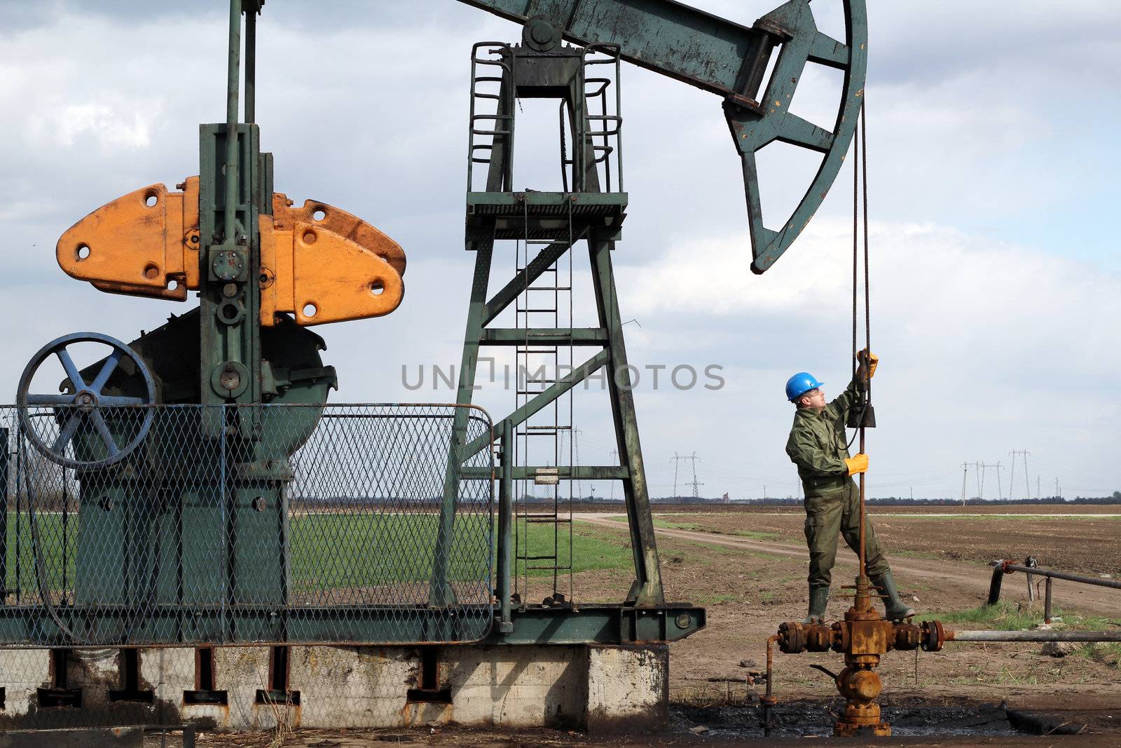 oil worker standing at pipeline and check pump jack