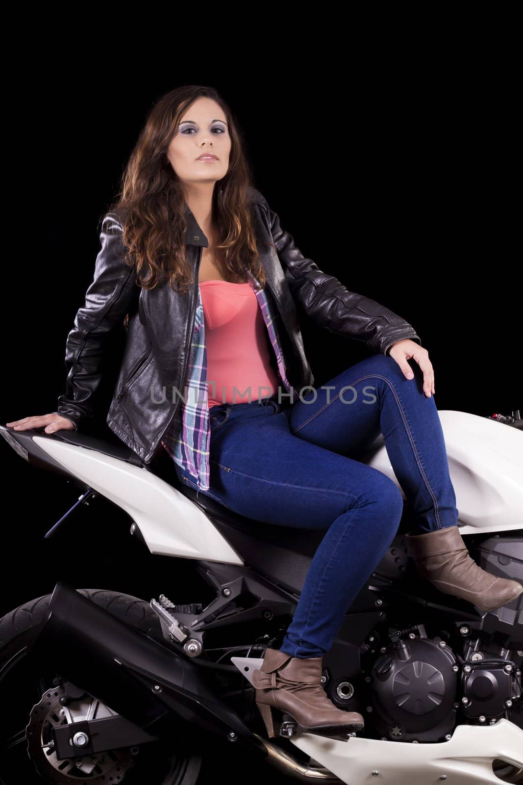 View of a beautiful young girl next to a white motorbike in a studio environment. 