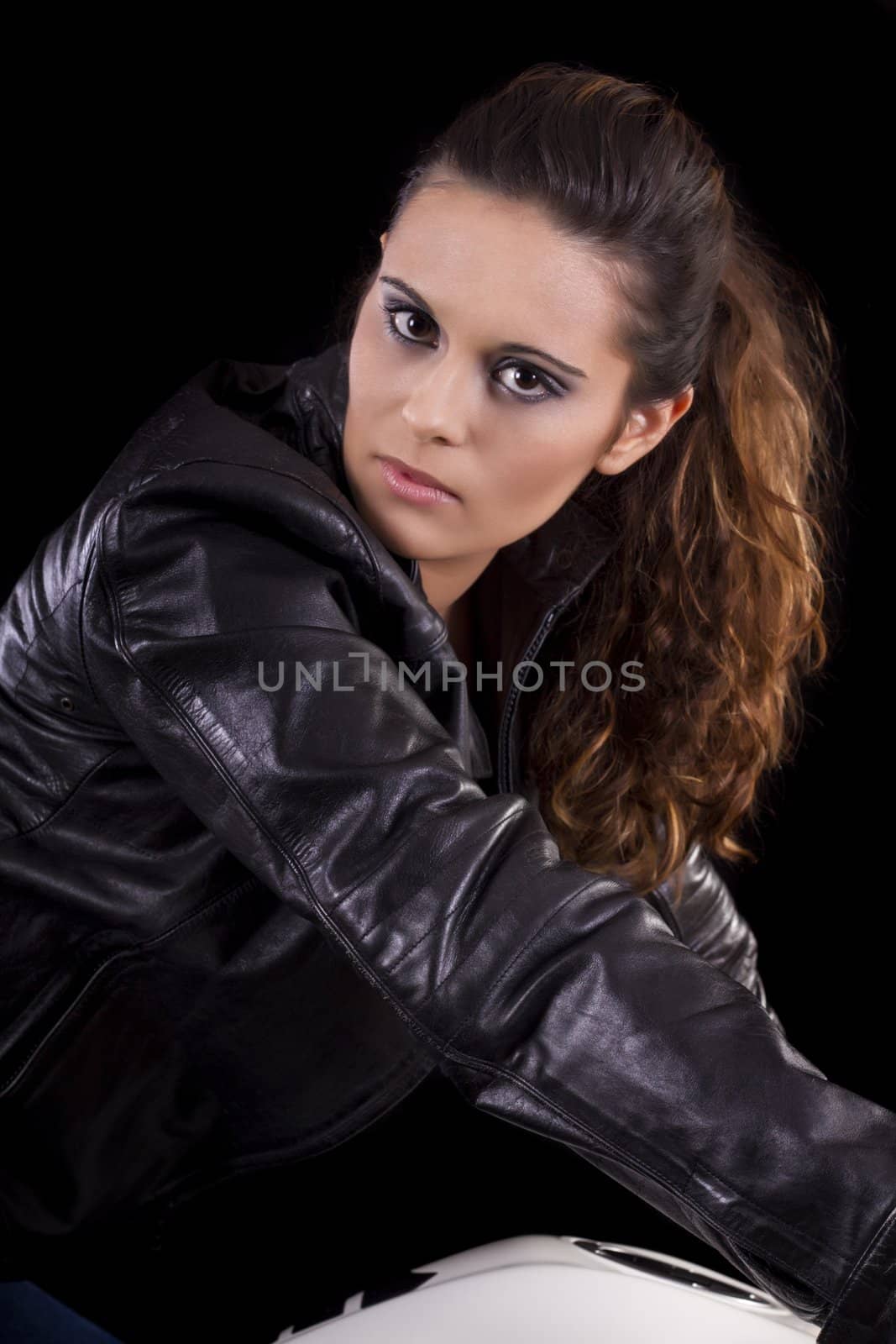 View of a beautiful young girl next to a white motorbike in a studio environment. 