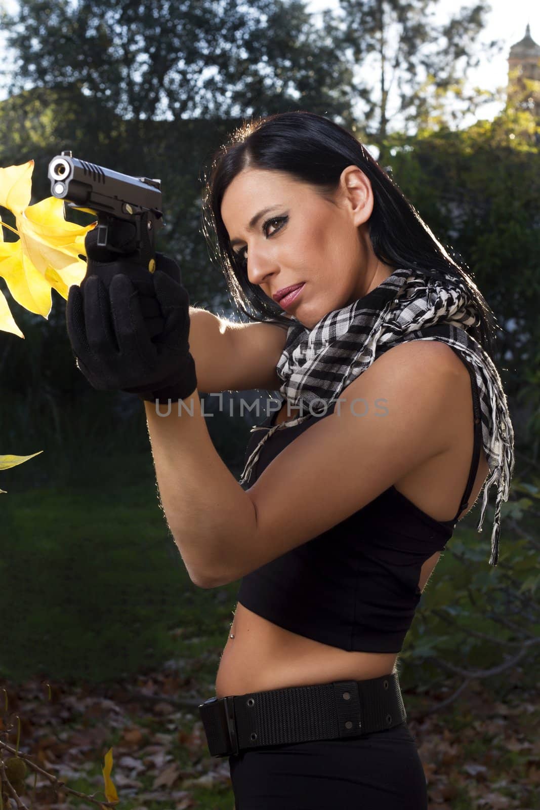 View of a beautiful action girl holding a weapon in a outdoor location.