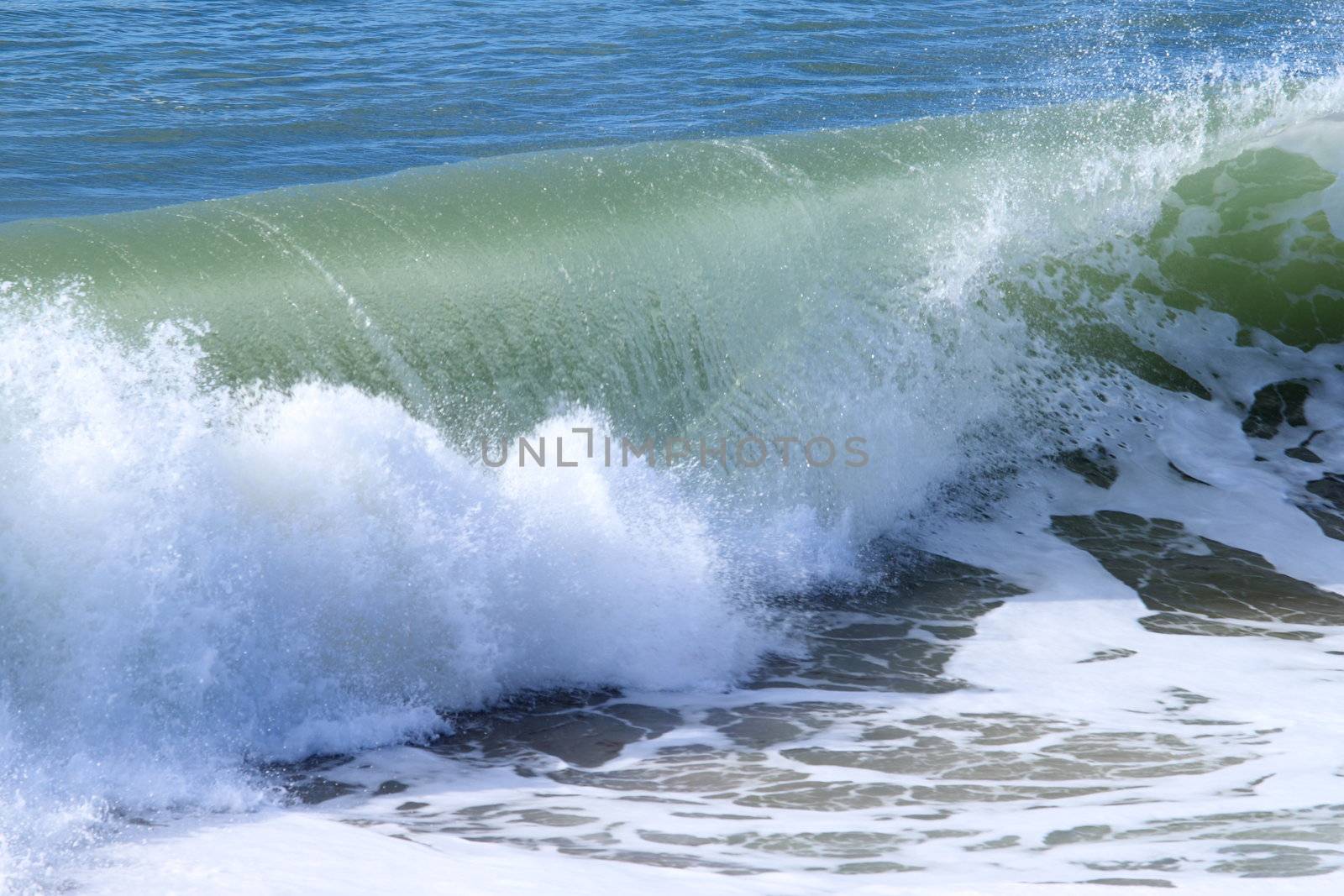 Closeup of a wave breaking near the beach.