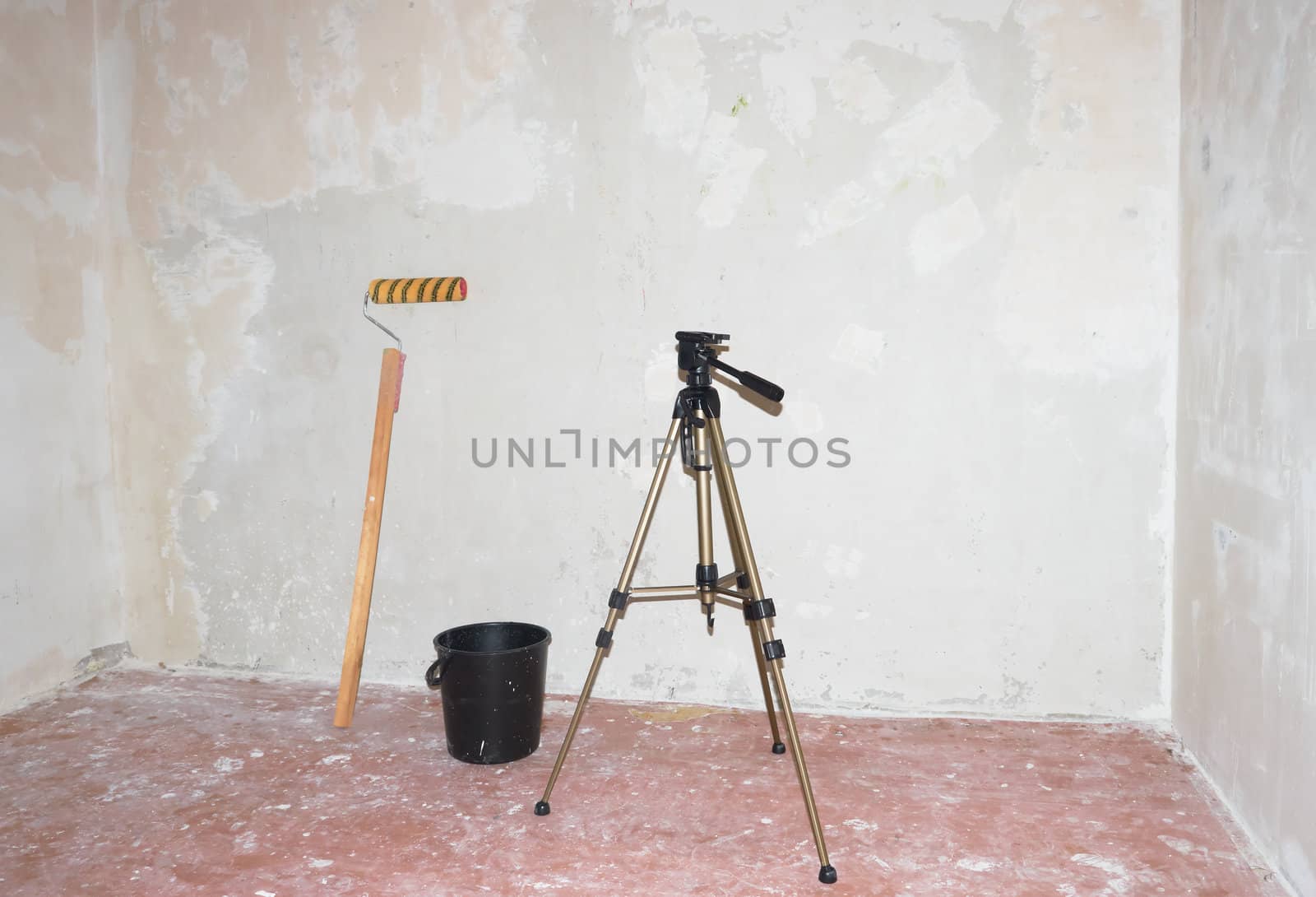 Roller for  putty, bucket and a tripod against the background of putty walls
