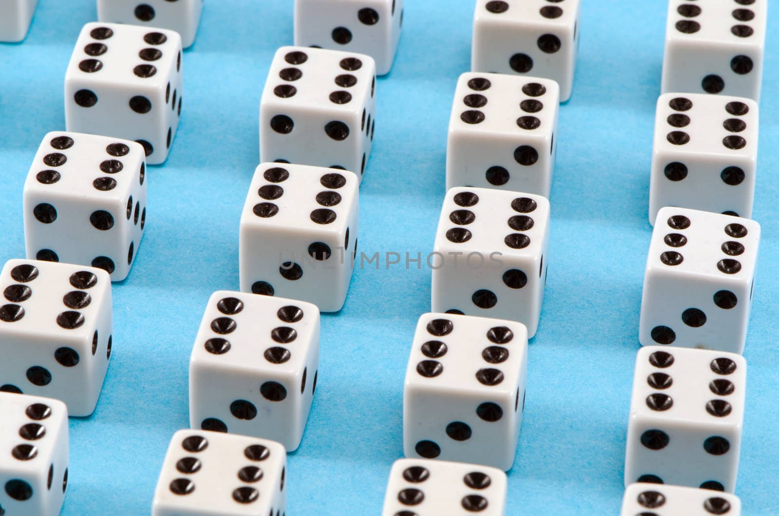 closeup of white gamble dice with six black dots on blue background.