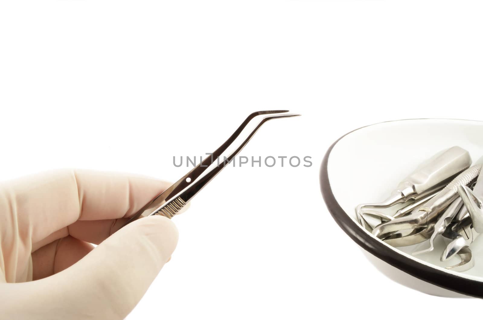 Tweezers in hand,gloved, and a set of medical dental tools