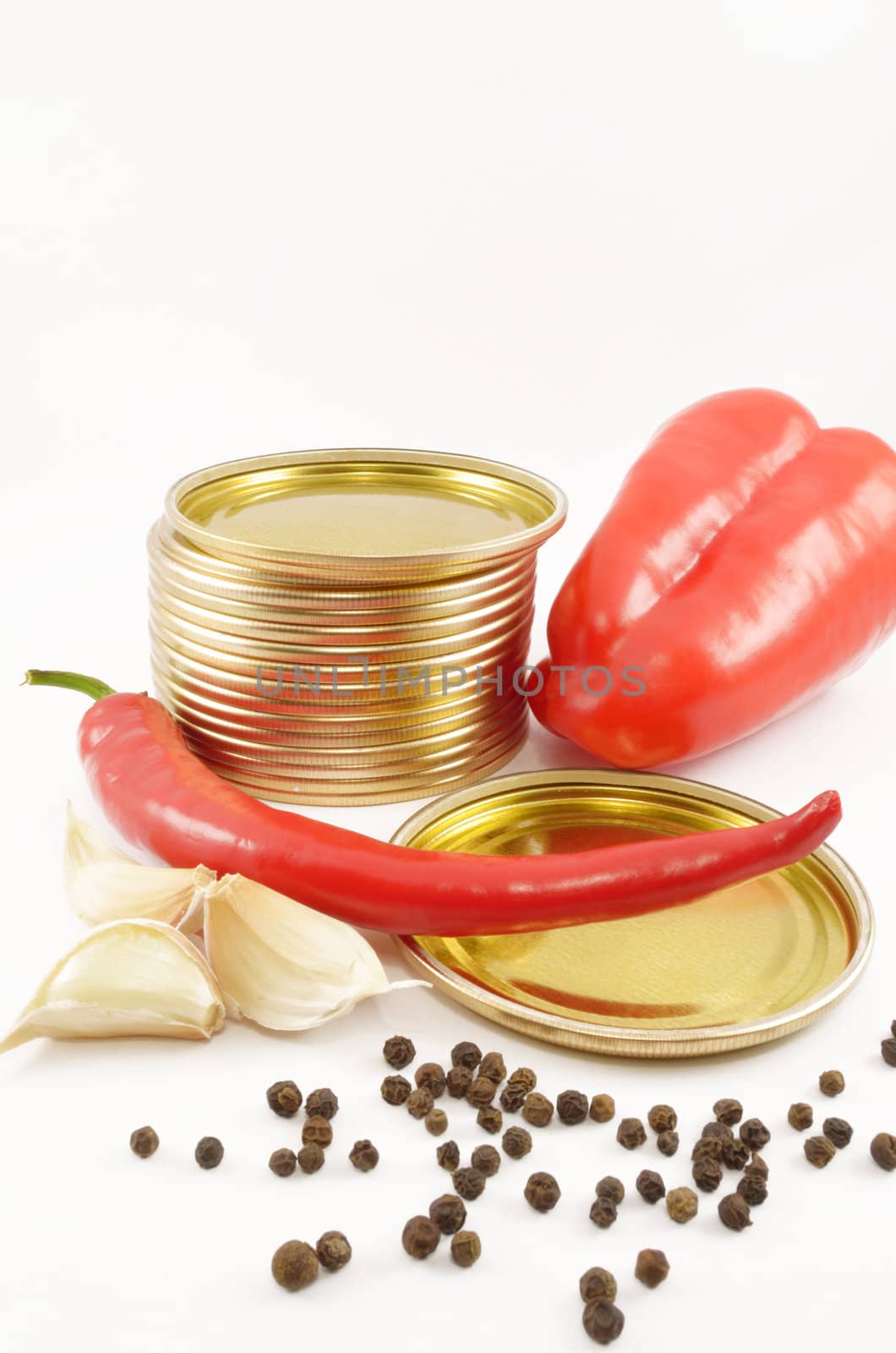 Sweet and sharp pepper, fragrant pepper, garlic and metal covers for cans on the isolated white background