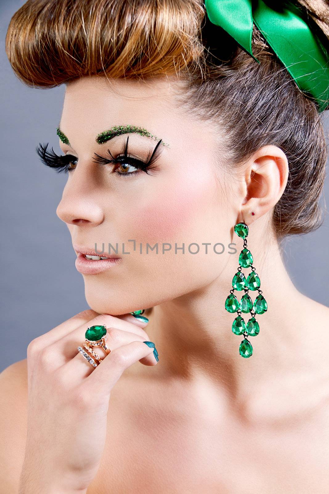 brunette woman with green jewelery and accssesoires on grey background