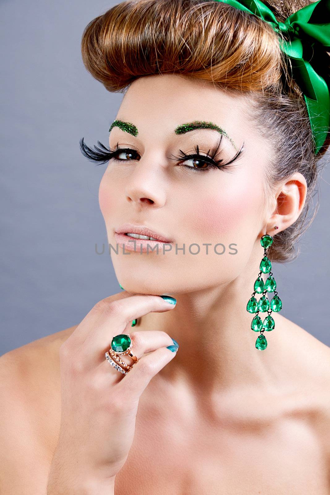 brunette woman with green jewelery and accssesoires on grey background