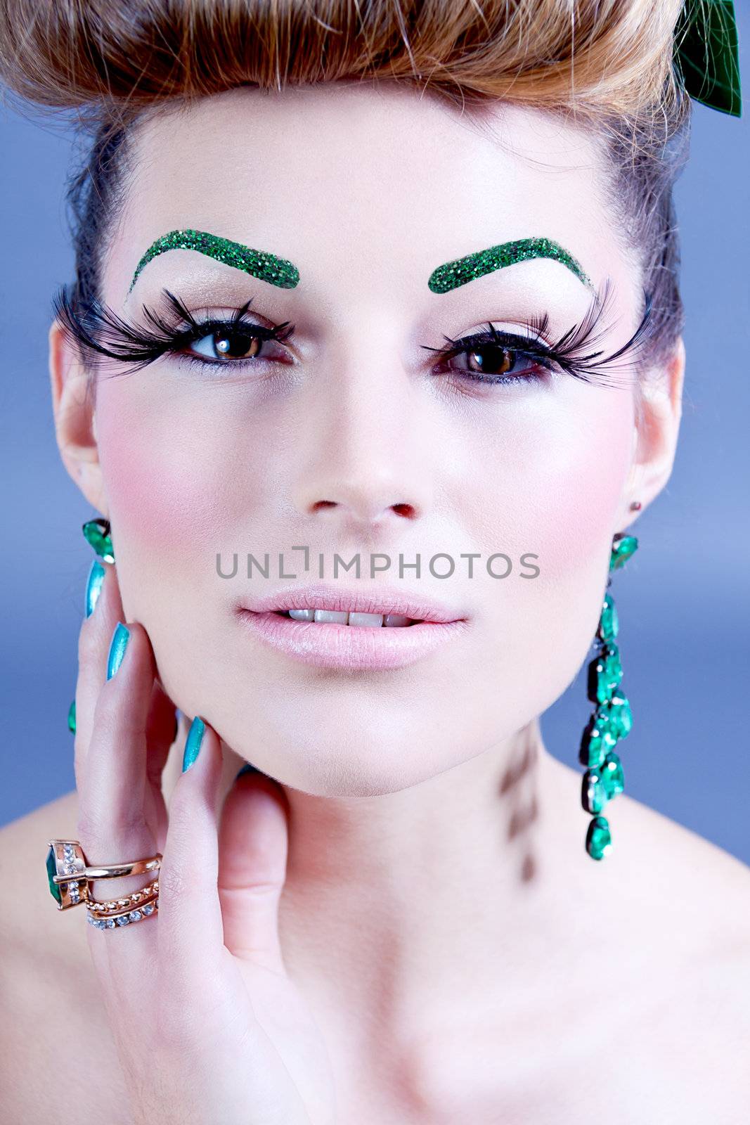 brunette woman with green jewelery and accssesoires on grey background