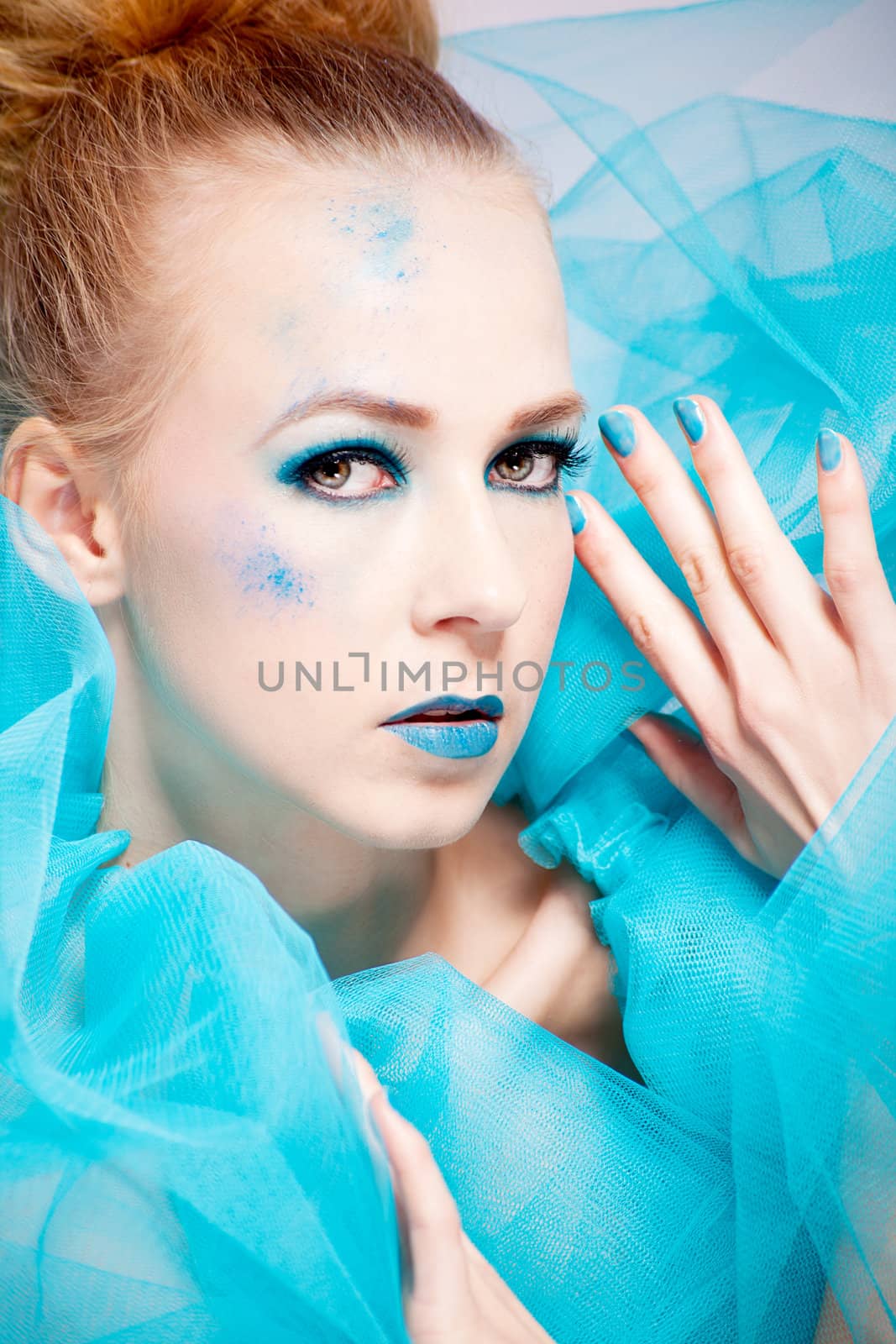 beautiful woman with extreme colorfull make up in turquoise portrait