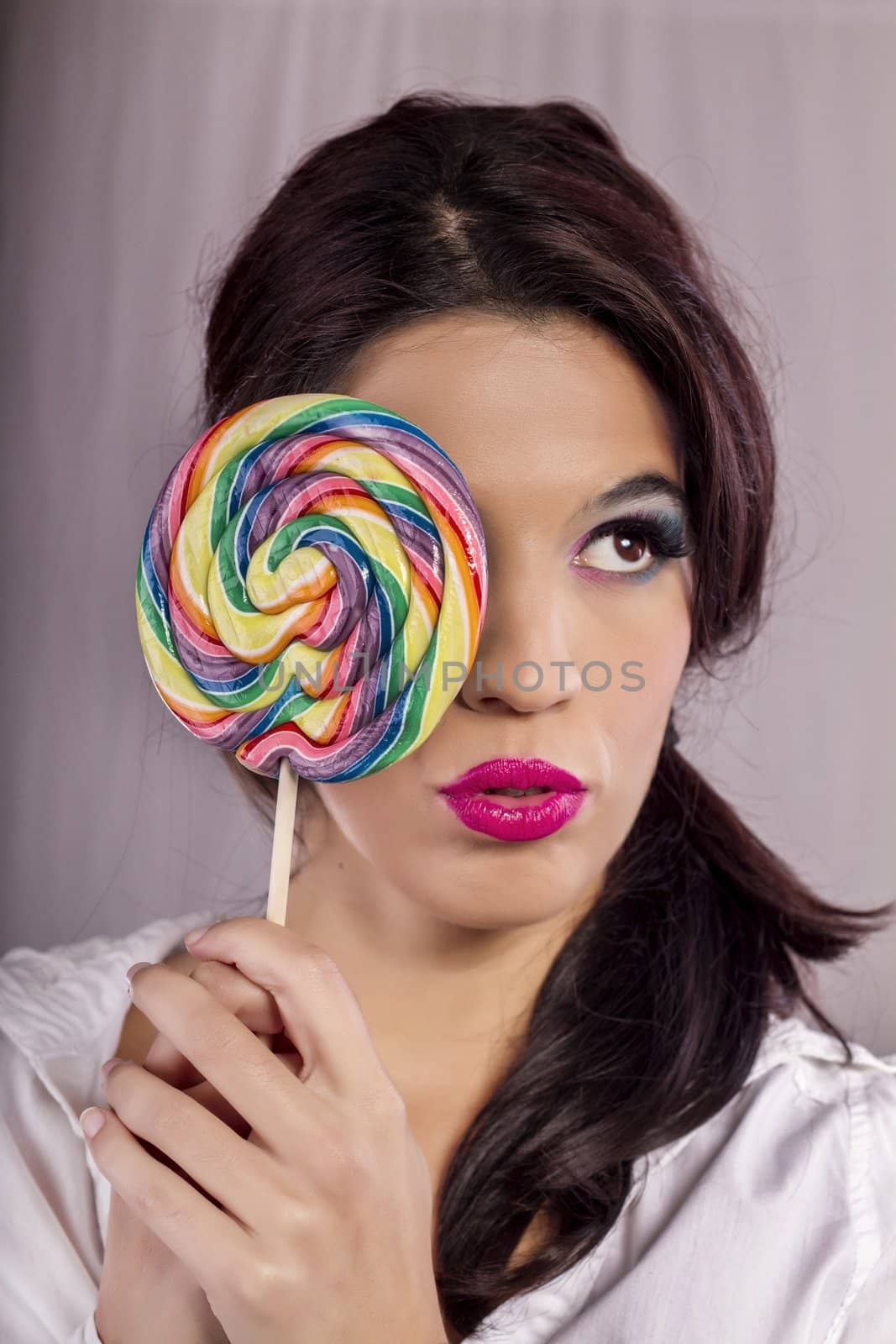 View of a beautiful girl with a colorful lollipop. 