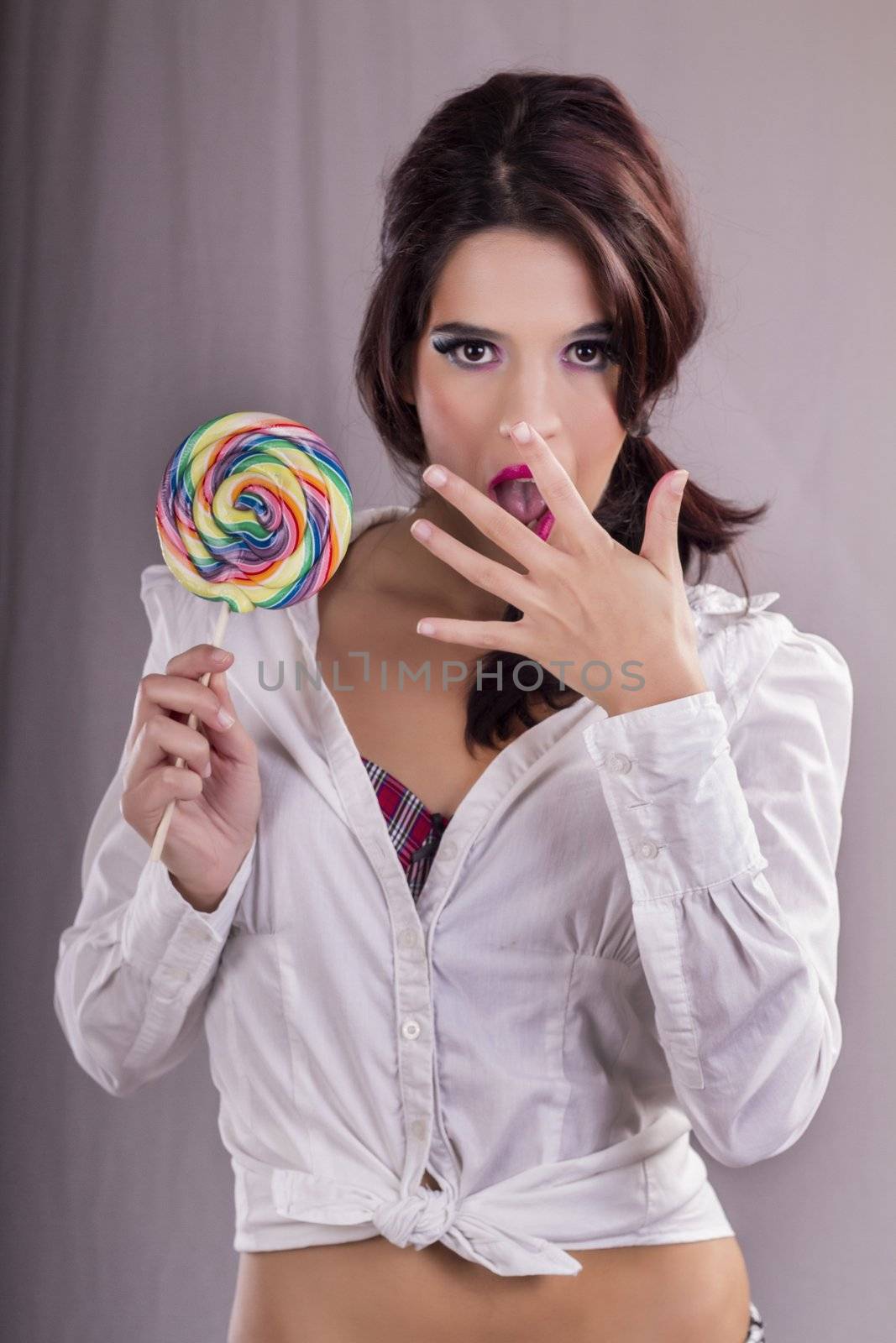 View of a beautiful girl with a colorful lollipop. 