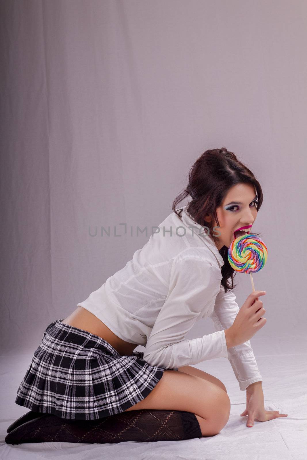 View of a beautiful girl with a colorful lollipop. 