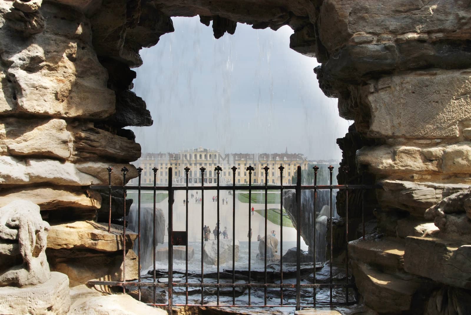 View of a Schonbrunn palace at Vienna, Austria through a window in a wall with a waterfall