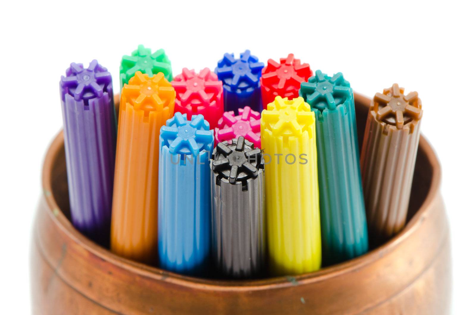 Closeup of motley colorful felt-tip pens in copper bowl isolated on white background.