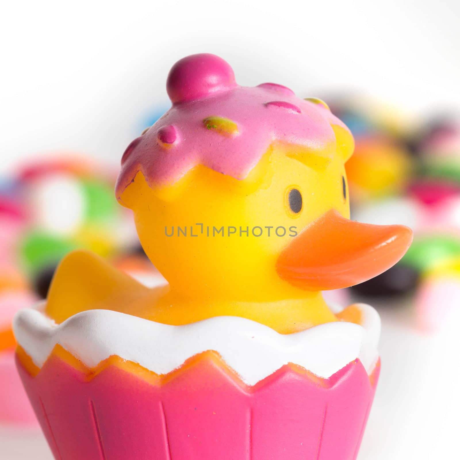 Easter rubber ducks with colorful jelly beans  out of focus in the background.  Isolated on white background