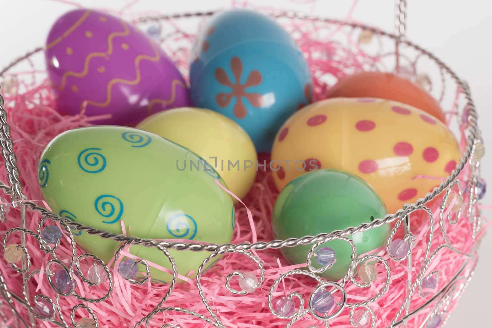 Decorated Easter eggs in Easter basket with pink decorative grass.  Isolated on white background.