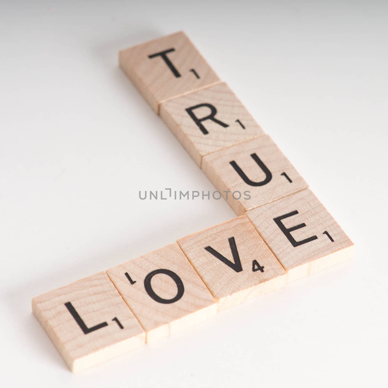 True Love Concept.  Wooden Scrabble letters spelling out phrase "True Love". Isolated on white background with light shadow