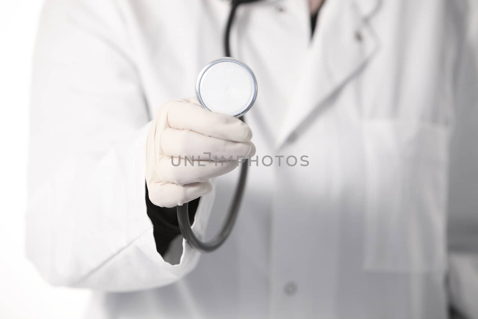 Cropped view of the gloved hand of a doctor in a labcoat holding a stethoscope with the disc pointing towards the camera