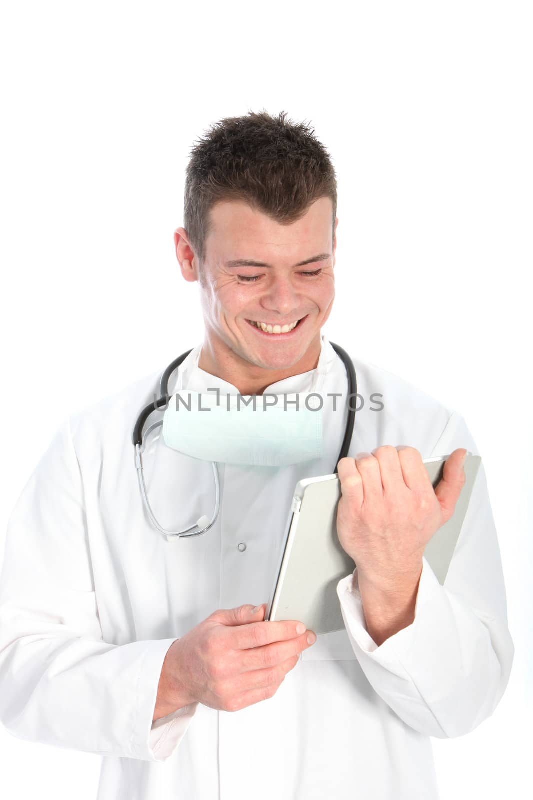 Handsome young male doctor wearing a labcoat and stethoscope smiling in glee at information on his tablet computer isolated on white
