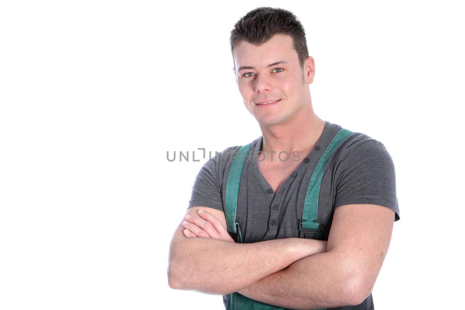 Handsome fit strong young man in dungarees standing with his arms folded looking at the camera with a smile islated on white