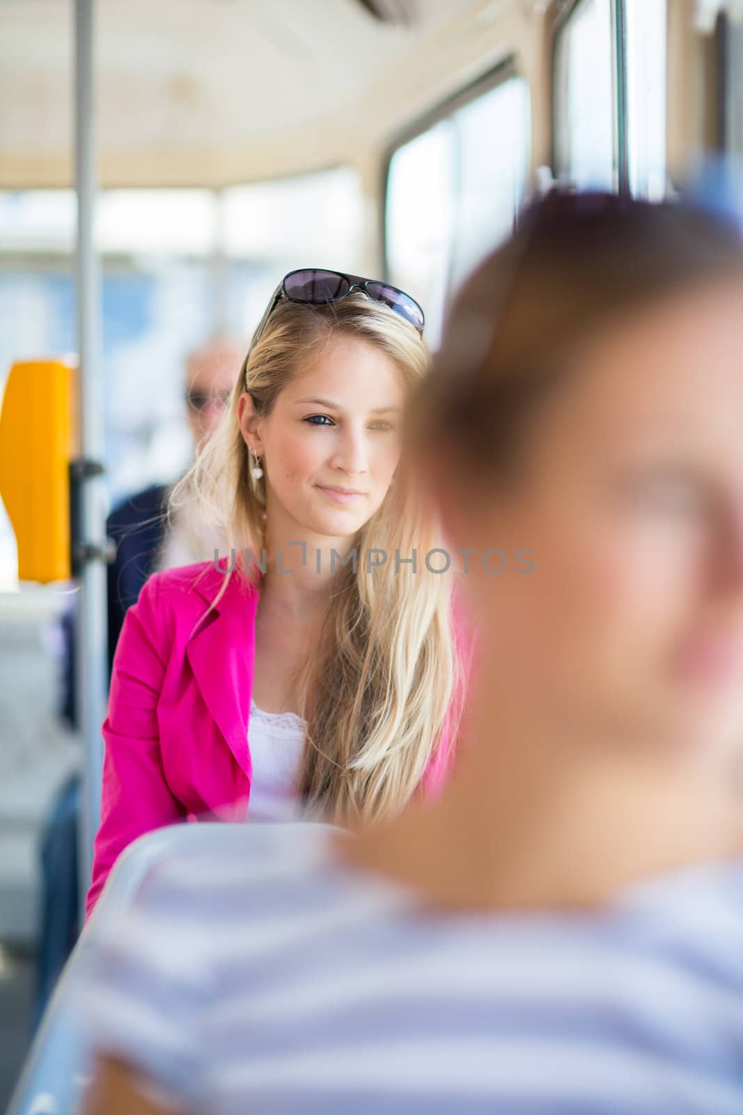 Pretty, young woman on a streetcar/tramway, during her commute to work/school (color toned image; shallow DOF)