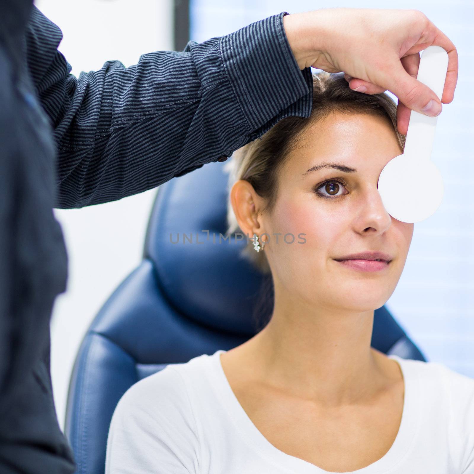 Optometry concept - pretty young woman having her eyes examined by an eye doctor/optometrist (color toned image; shallow DOF)