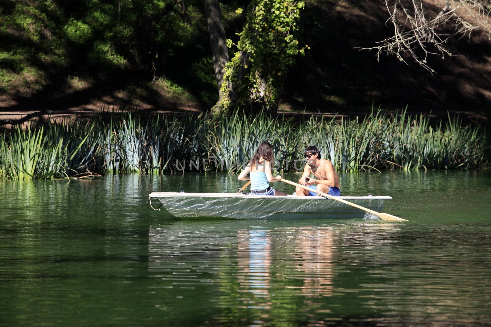 Happy man sitting in boat and looking at woman while floating