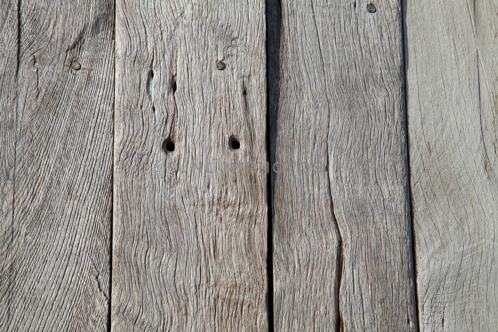 Planks of sun bleached oak with grain, joints, holes and cracks.