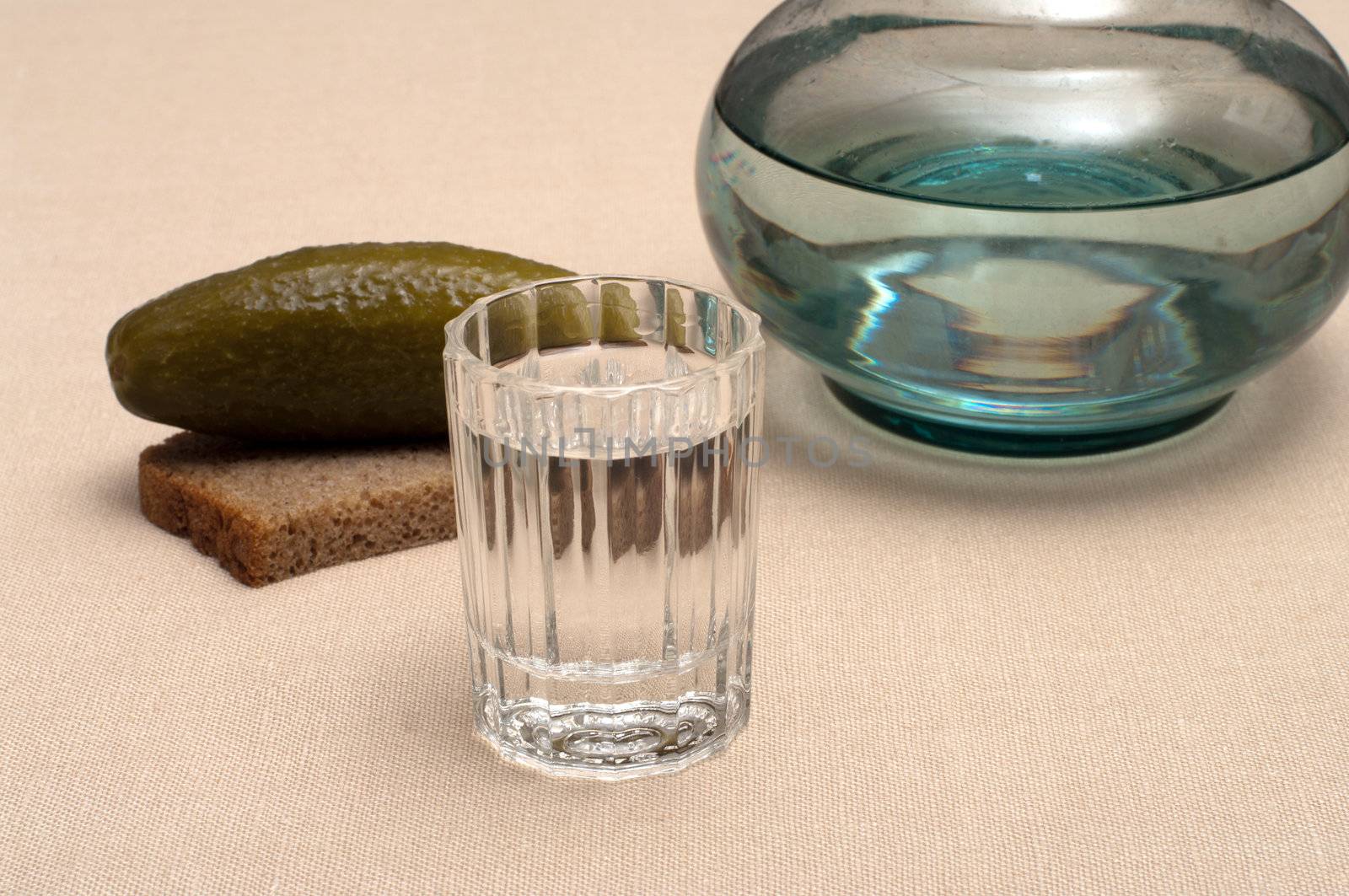 Wineglass of vodka pickles and rye bread close up.