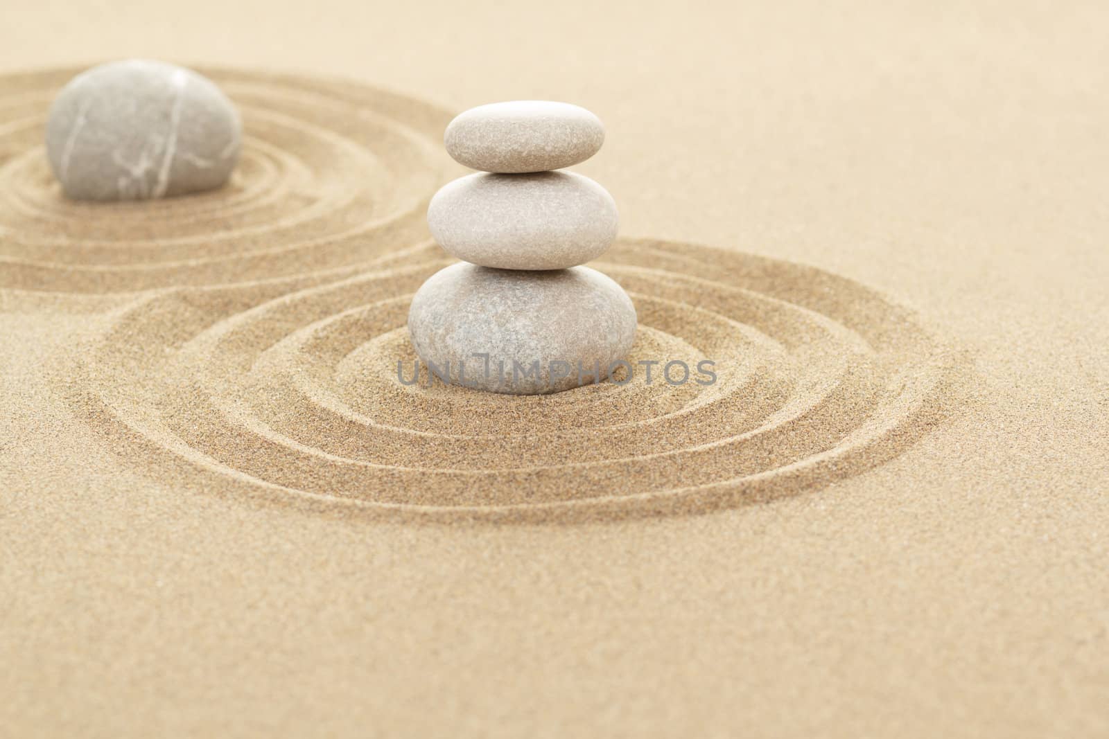 Balance of three zen stones in sand with shallow focus