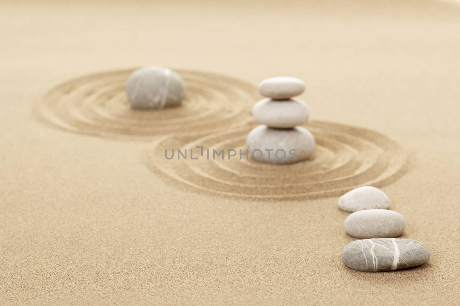 Balance of three zen stones in sand with shallow focus