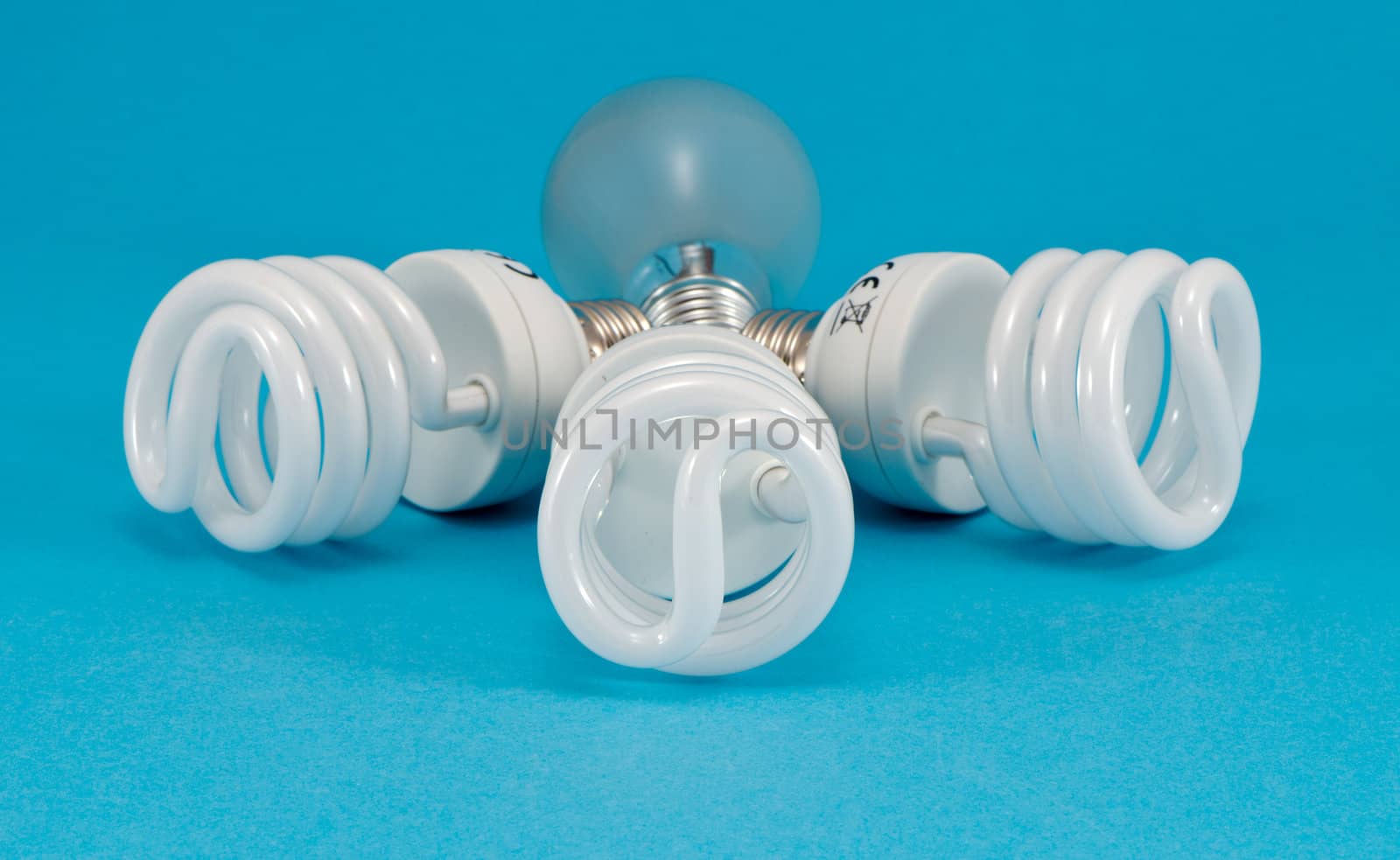 novel new modern fluorescent lights and old incandescent heat bulb on blue background. economic technology for less electricity energy consumption.
