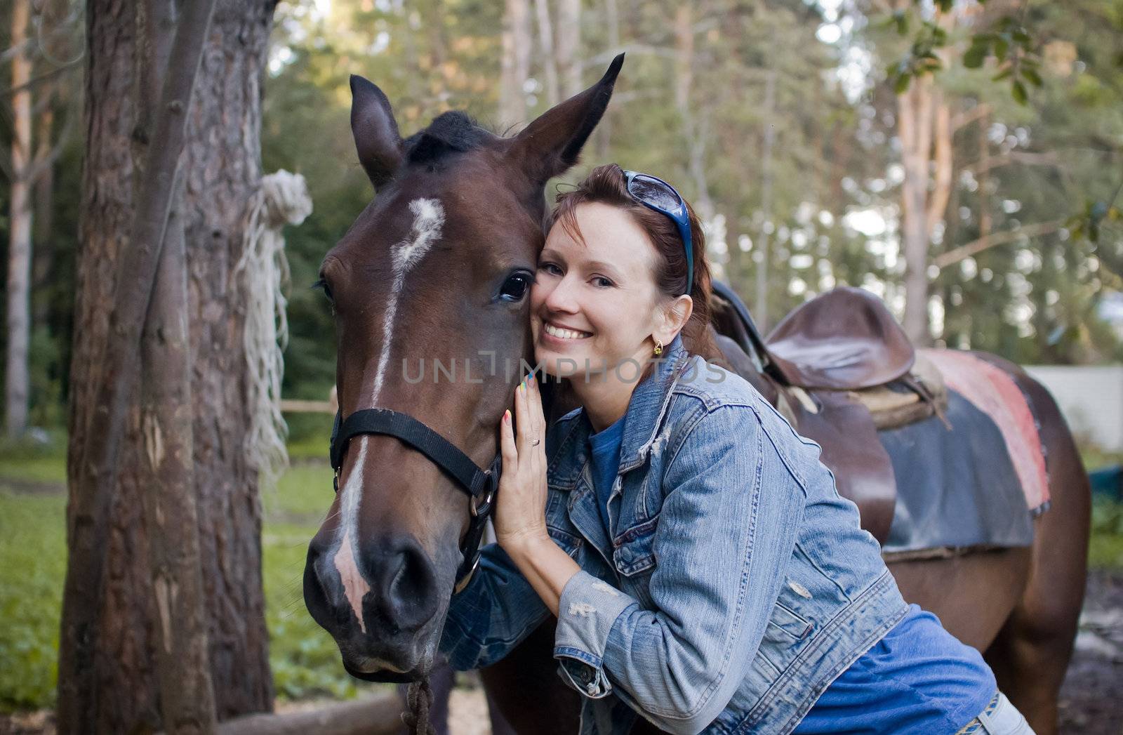 Young woman hugs brown horse after riding