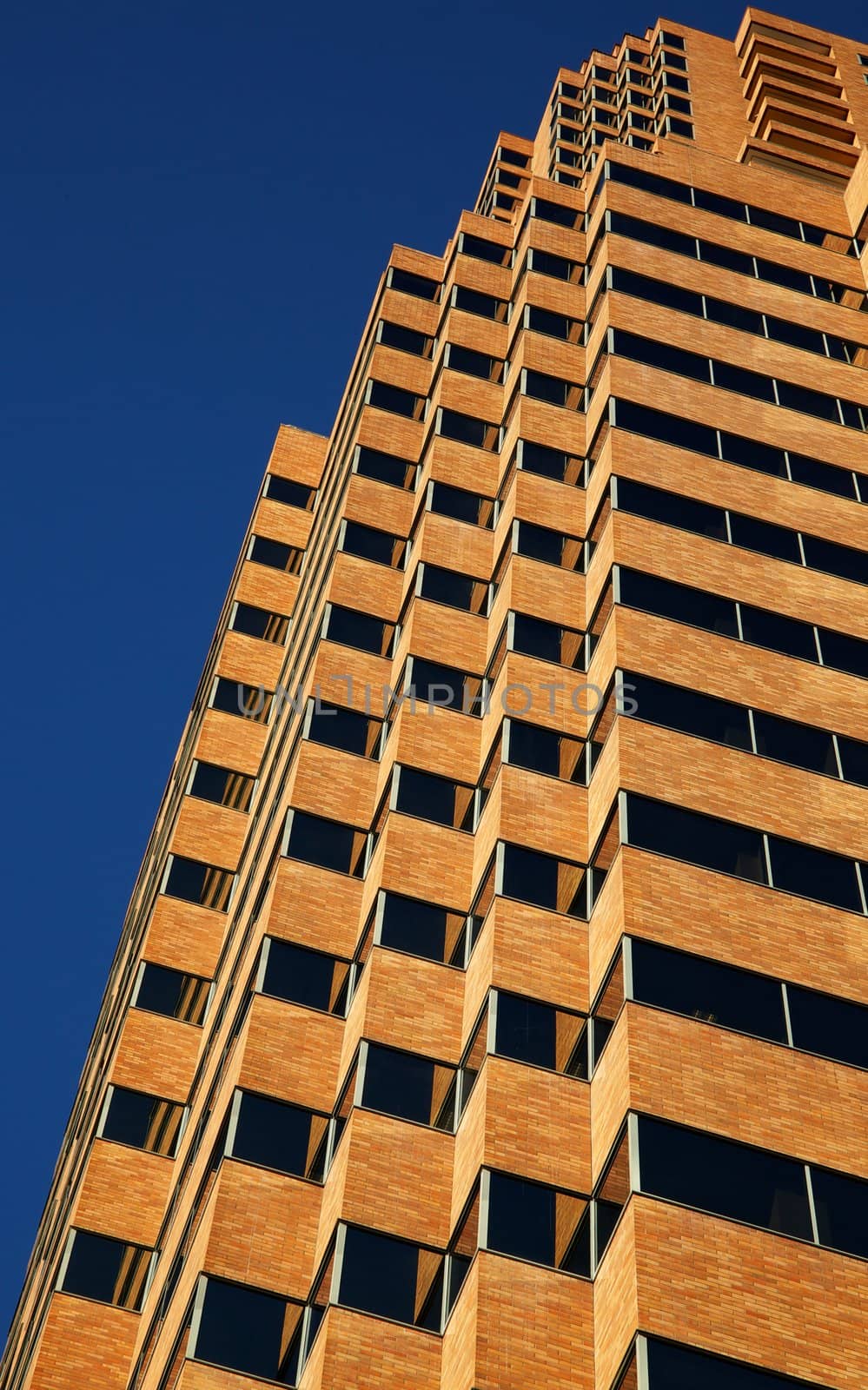 Close up vertical view of modern tan office building on a clear day