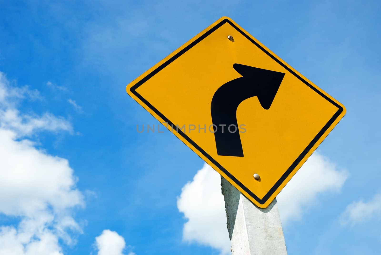 Road sign warning of dangerous left curve on blue sky