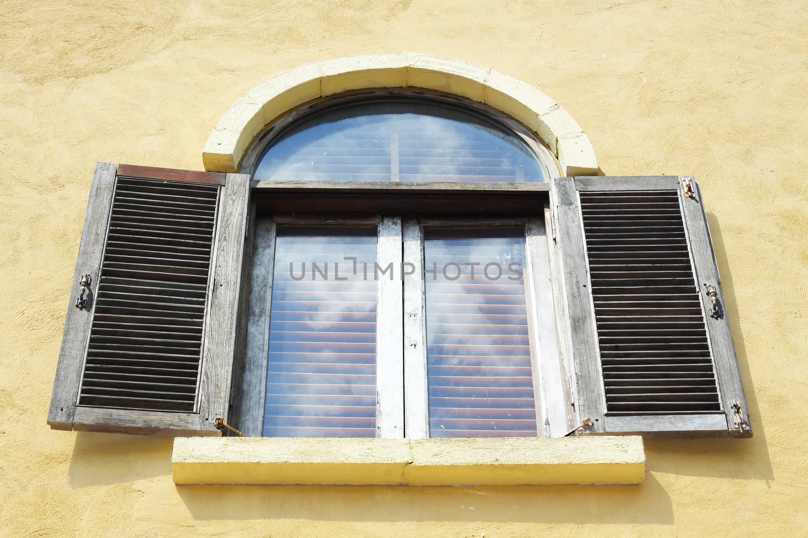 Old wooden window open on orange wall.