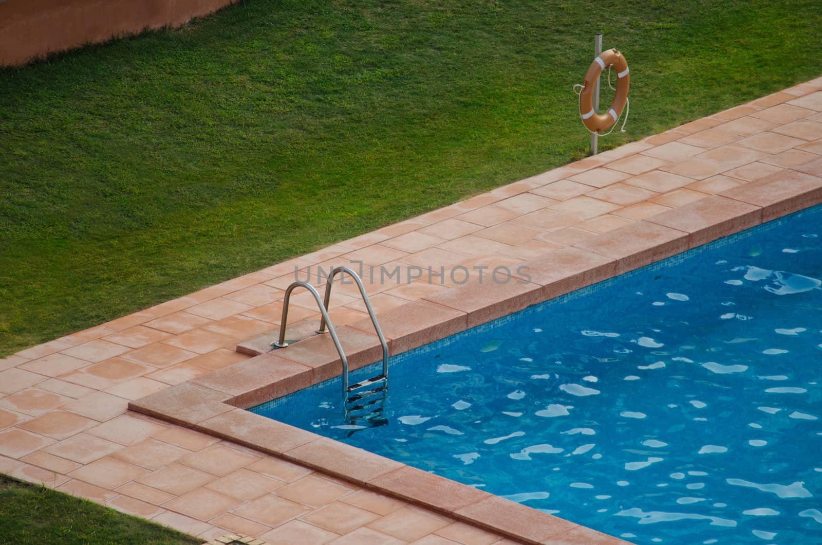 Corner of swimming pool outside with grass around it