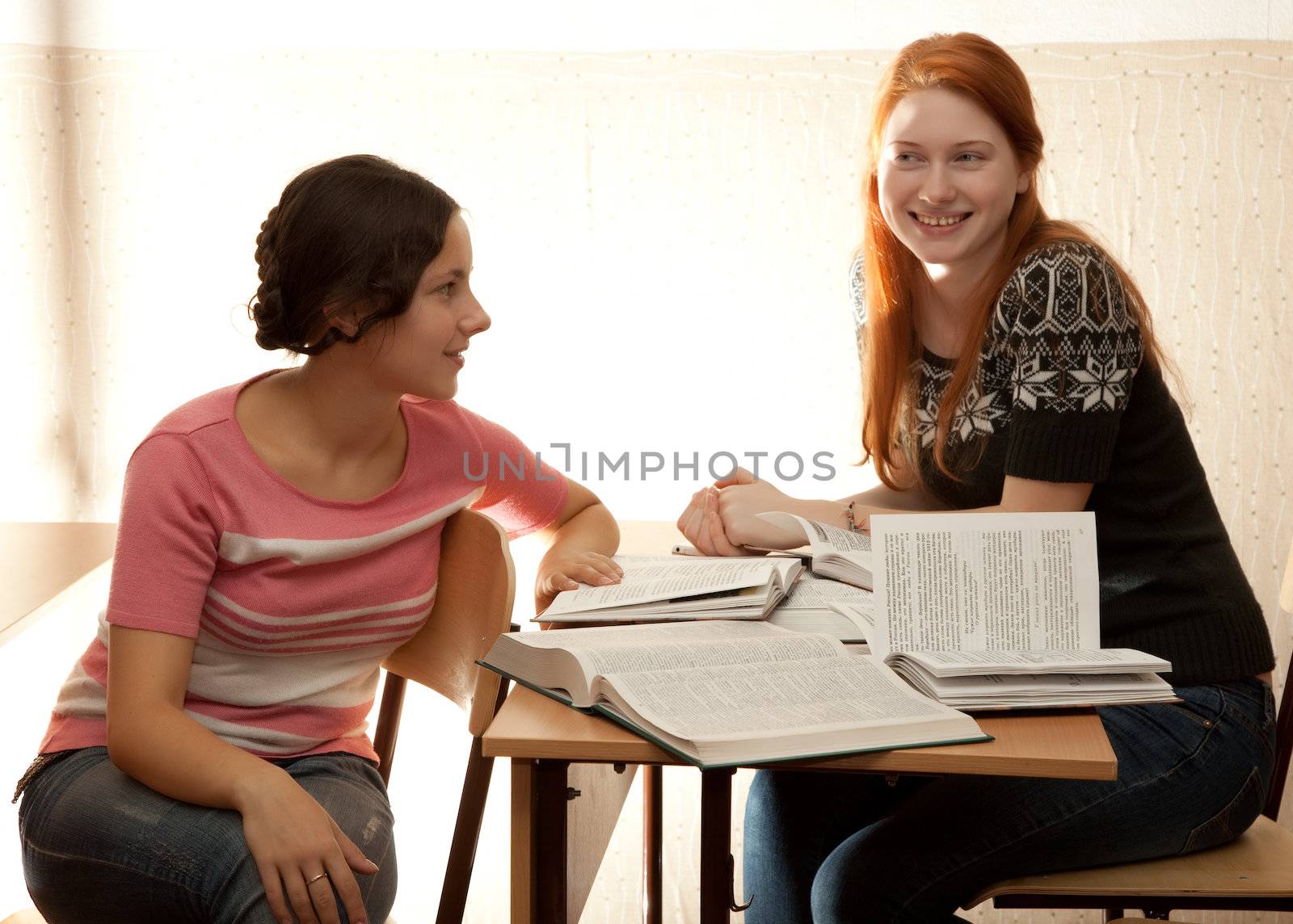 Two girls engage in a library in bright sunlight