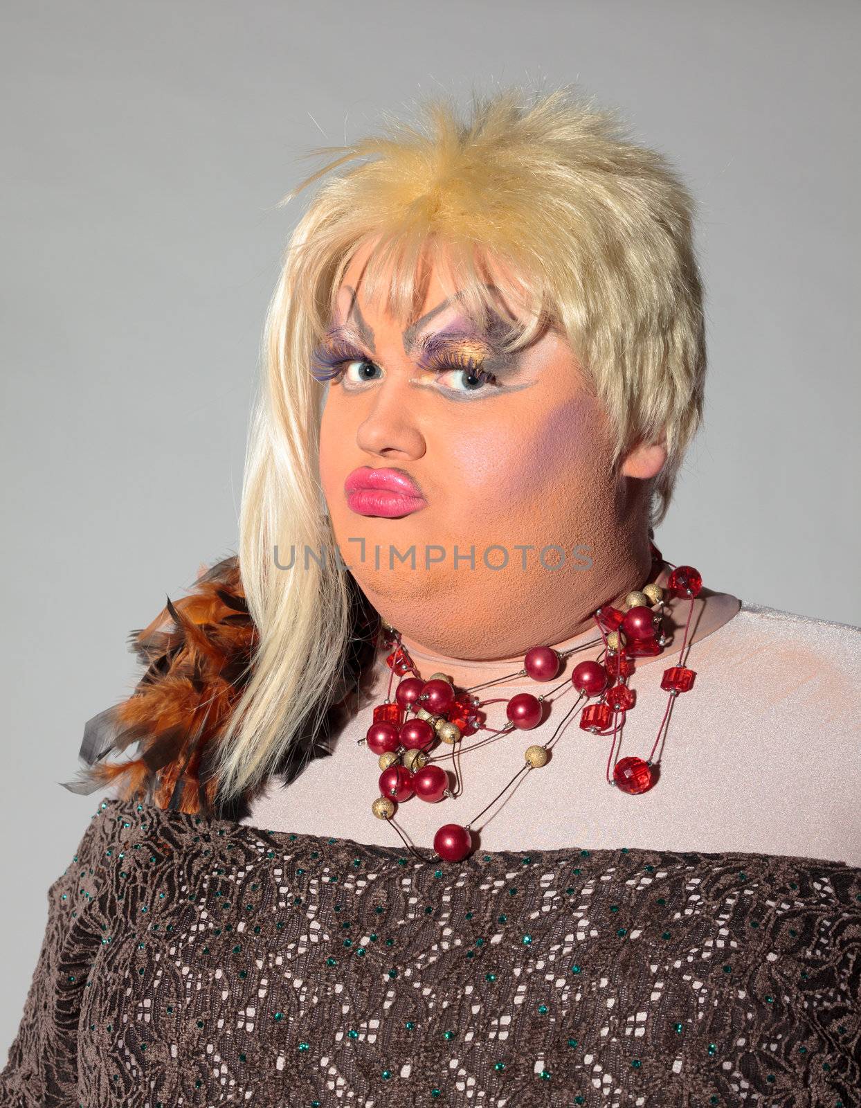 Cheerful man, Drag Queen, in a Female Suit, over gray background