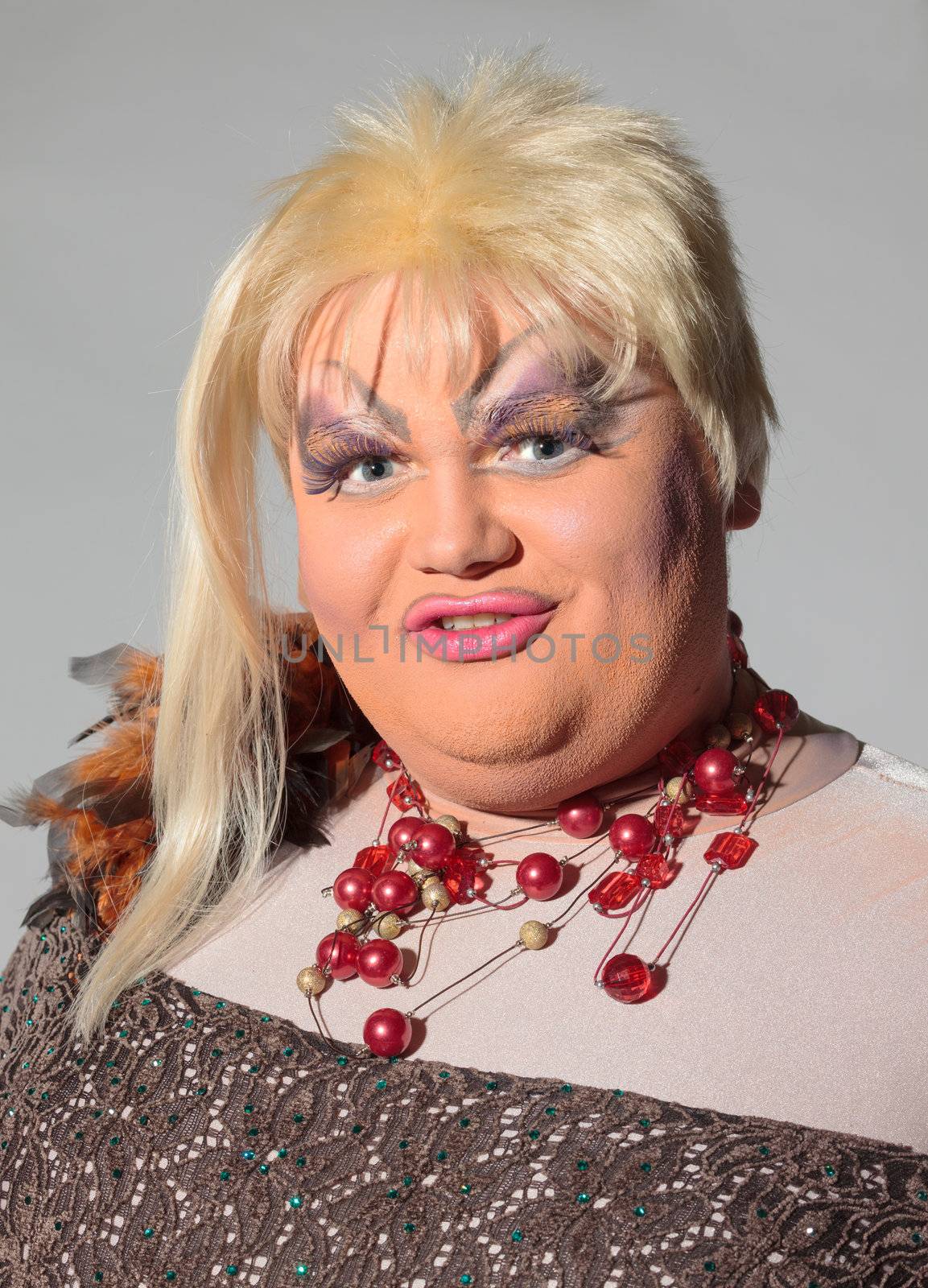 Cheerful man, Drag Queen, in a Female Suit, over gray background