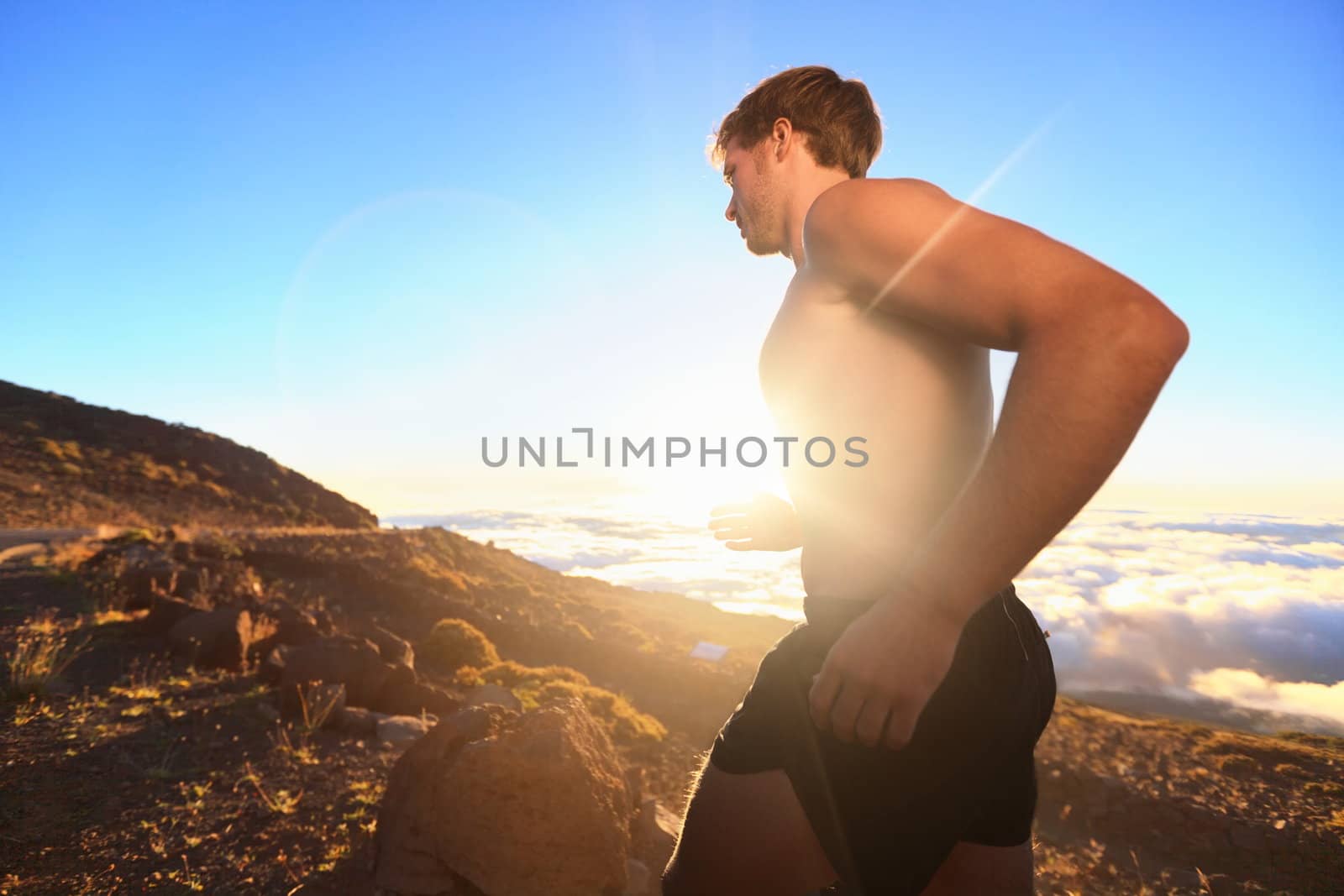 Runner athlete running. Sport man jogging outdoor in sunshine at sunset in scenic nature. Fit muscular male fitness athlete training trail running for marathon run. Sporty fit athletic man working out in topless outside.